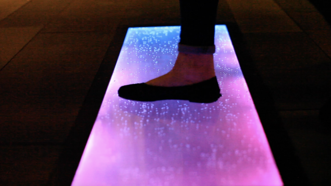 Close-up detail of Promenade pad — textured surface and glowing LED effect in ambient light